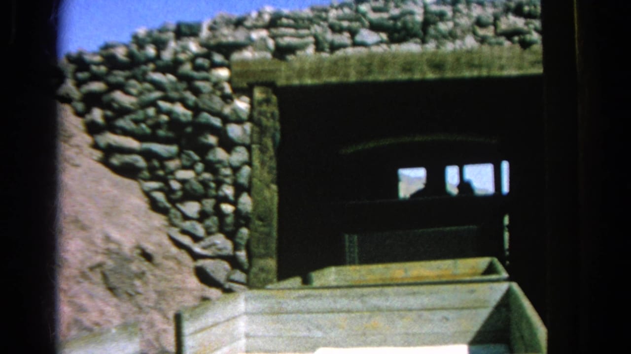 The train is mostly inside the stone-lined tunnel portal in this 1966 Silver Lake 8mm frame, with rough rockwork, shadowed opening, and a foreground railcar edge.