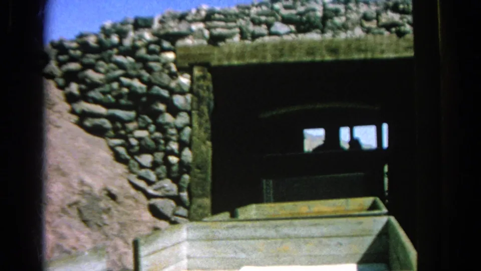 The train is mostly inside the stone-lined tunnel portal in this 1966 Silver Lake 8mm frame, with rough rockwork, shadowed opening, and a foreground railcar edge.