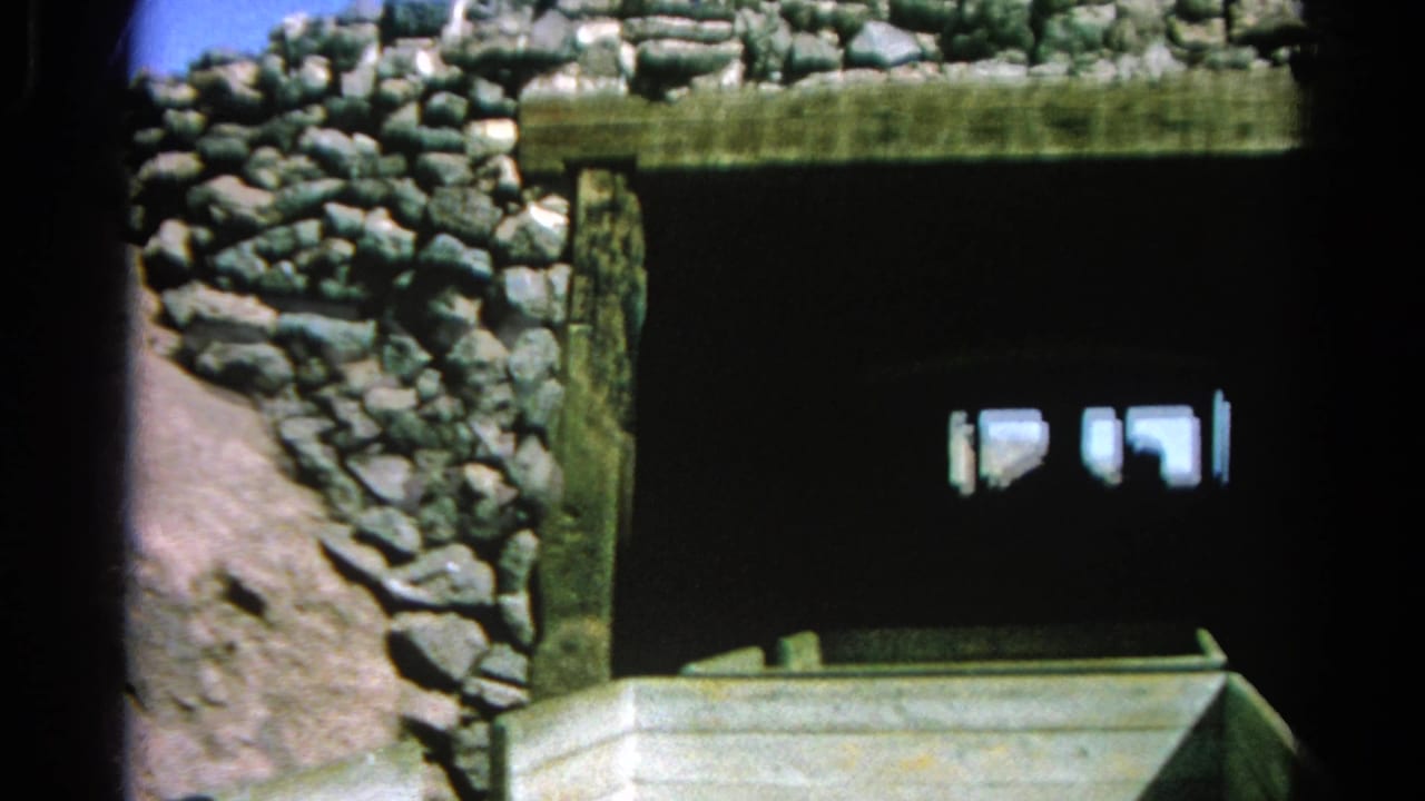 Stone tunnel entrance with the front of a wooden train car in shadow.