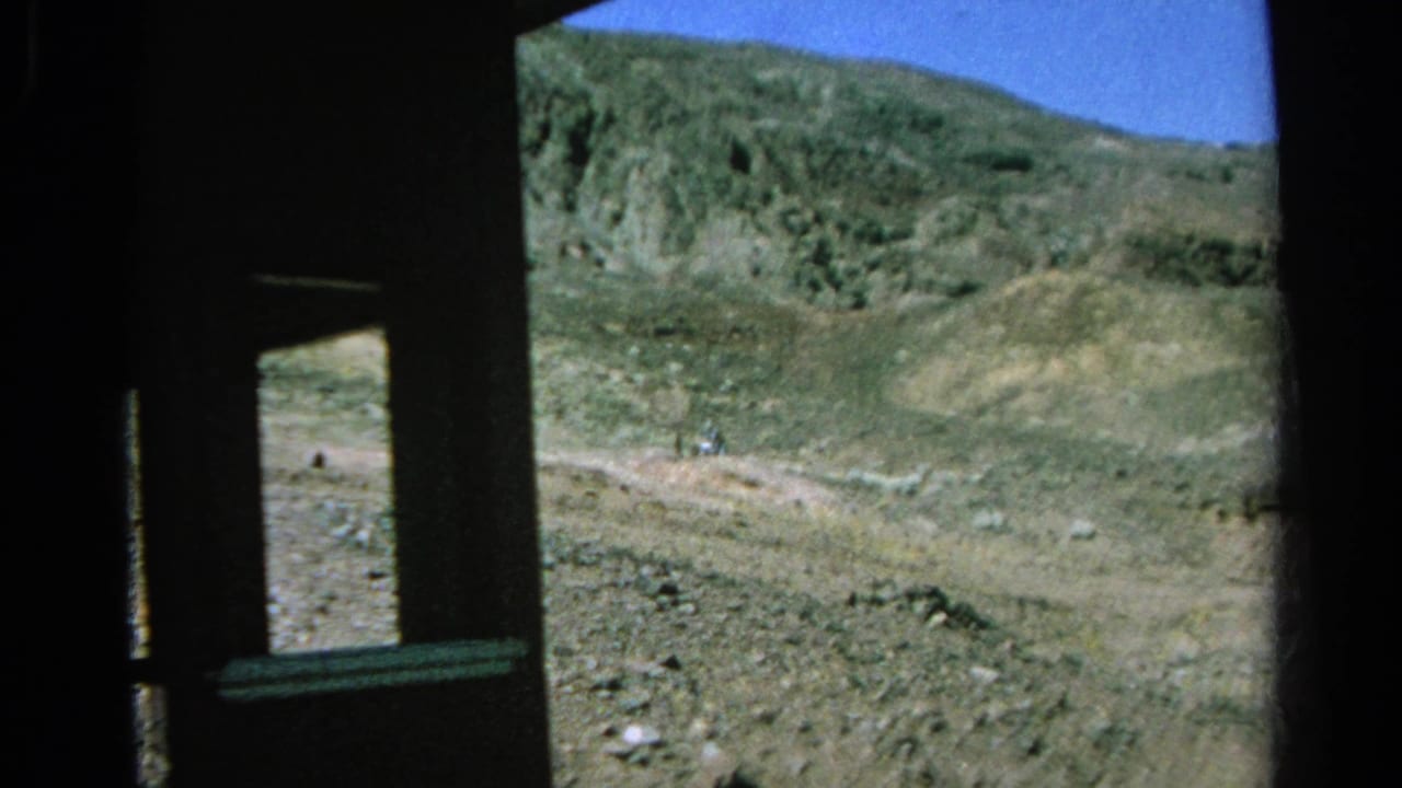 The train passes a rocky Silver Lake slope, with the 8mm camera looking out through a narrow dark window frame.