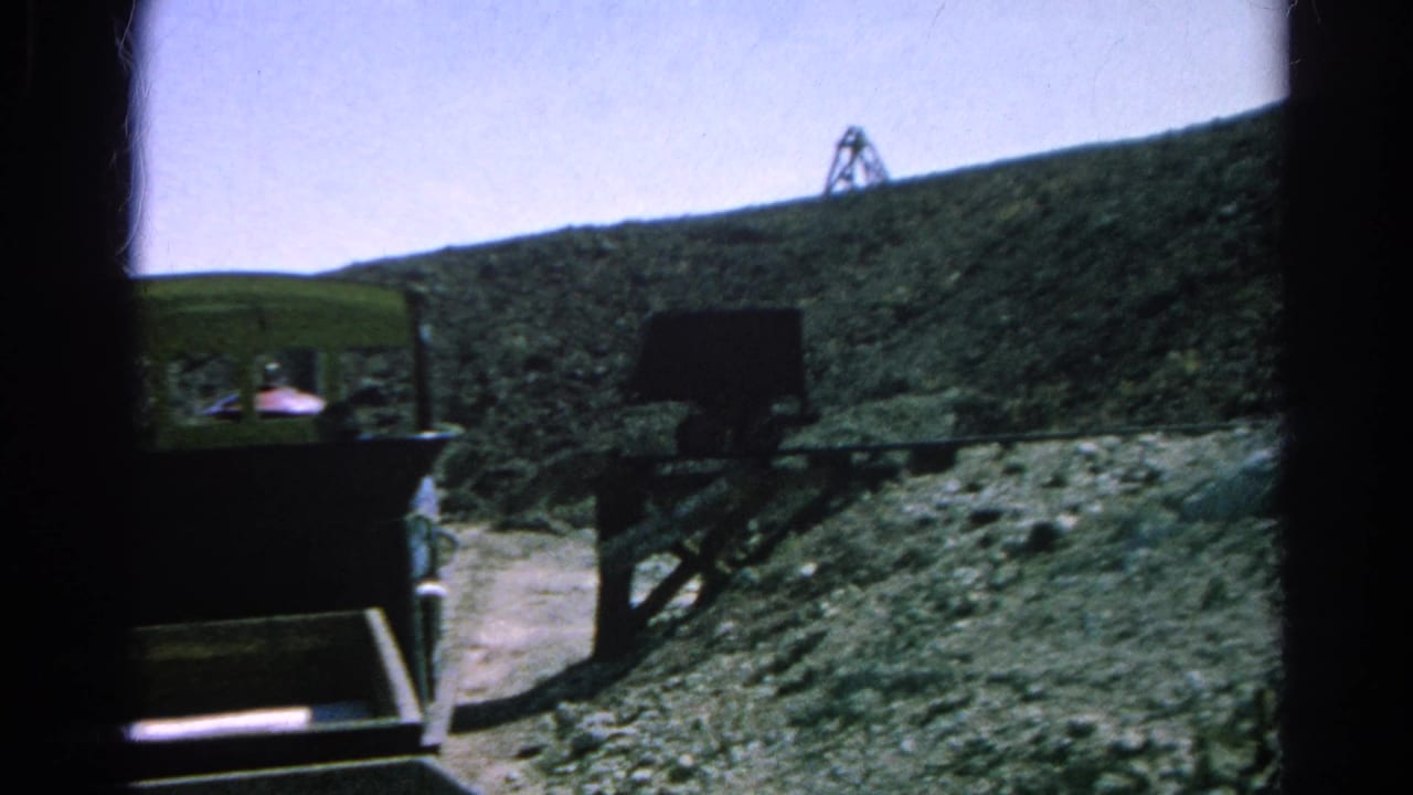 1966 Silver Lake, California 8mm frame showing a green mining tram beside dark rail supports on a steep rocky slope.