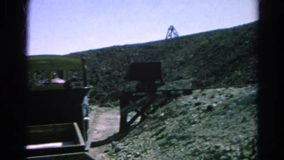 1966 Silver Lake, California 8mm frame showing a green mining tram beside dark rail supports on a steep rocky slope.