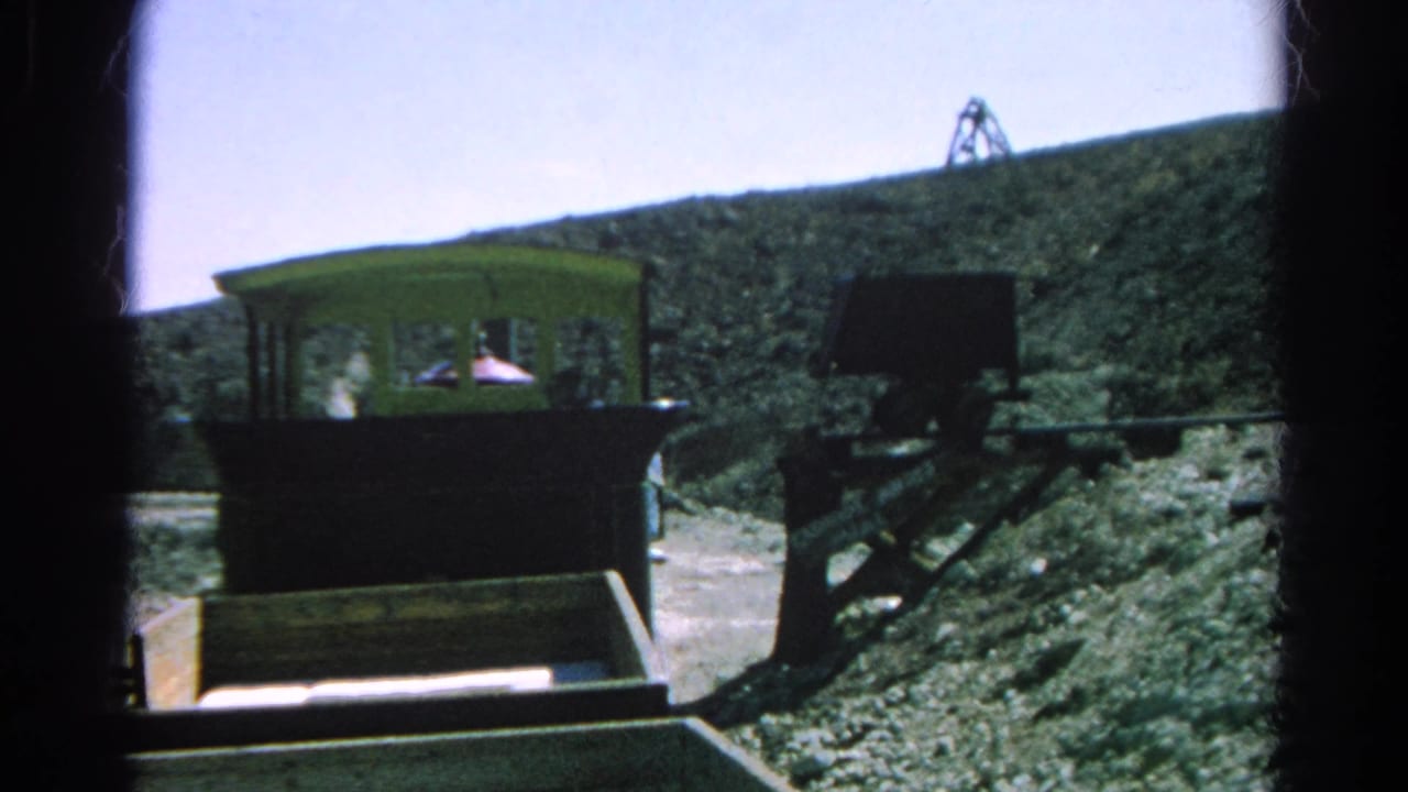 Mining tram car and support frame on a rocky slope with a derrick-like structure on the ridge.