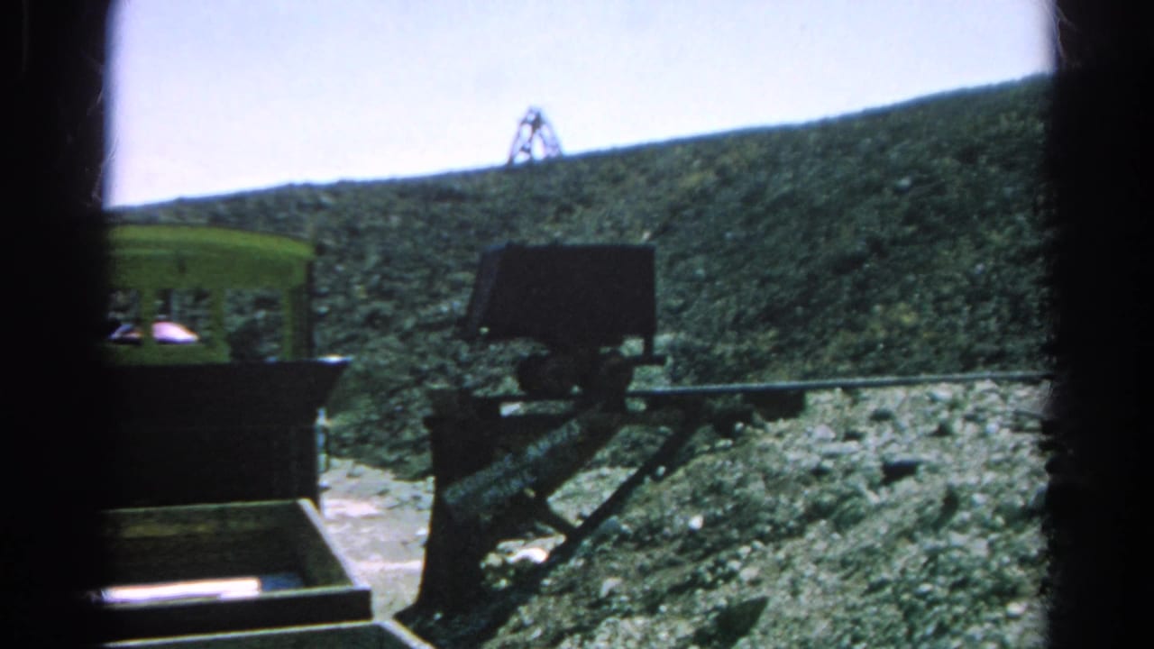 1966 8mm frame from Silver Lake showing the tram moving past a dark support structure on a rocky mountain grade.