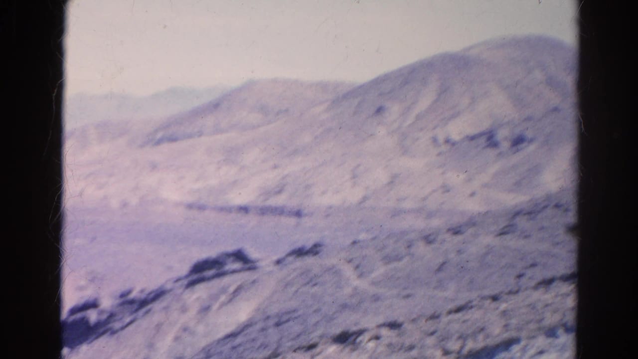 A rounded arid hillside fills the 1966 8mm frame, with rocky foreground and faded home-movie color in the Silver Lake area.