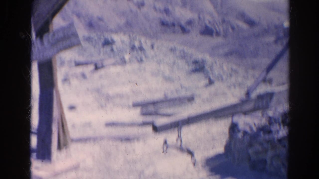 Rocky hillside with scattered wooden boards and dark film borders.