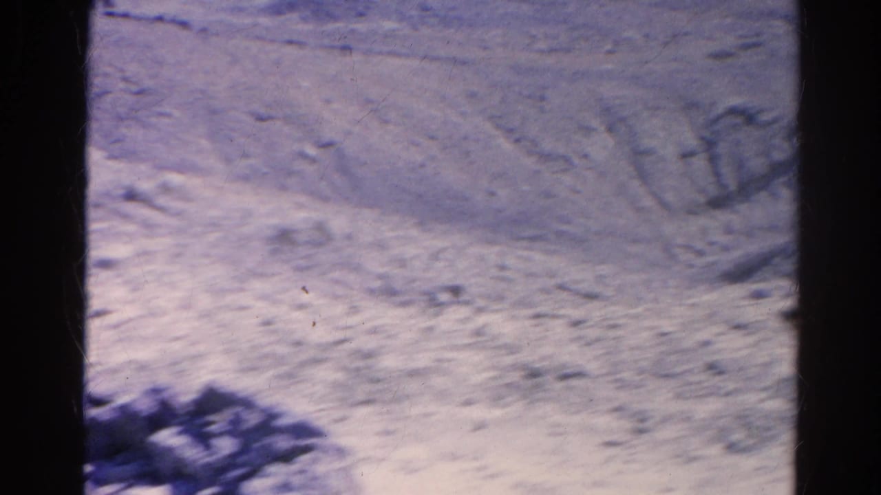 Soft 8mm frame showing washed-out rocky terrain in Silver Lake with faint wooden frames or posts and scattered debris.
