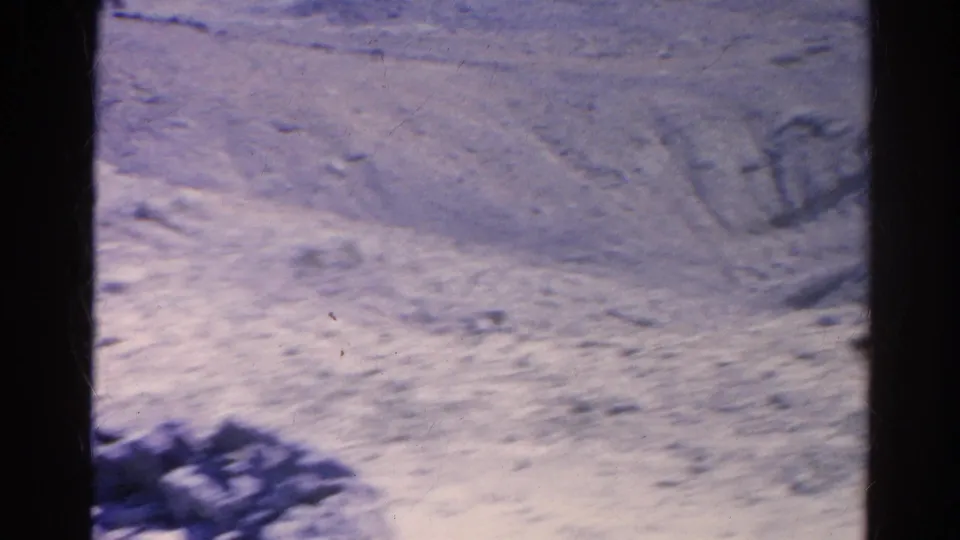 Soft 8mm frame showing washed-out rocky terrain in Silver Lake with faint wooden frames or posts and scattered debris.