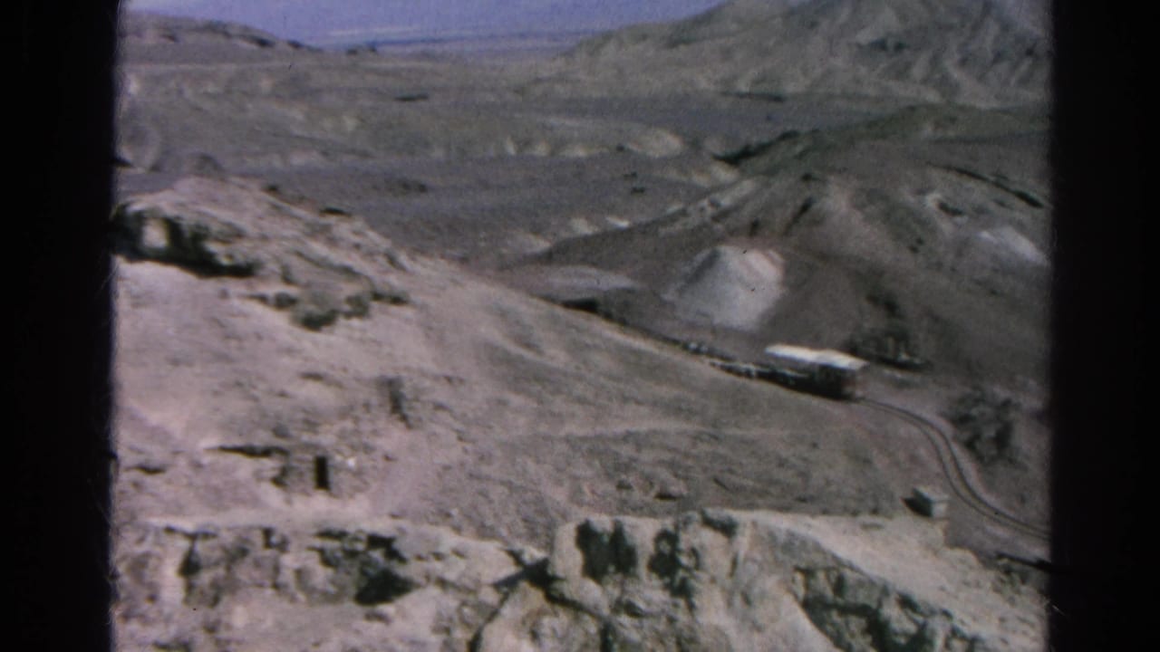 1966 Silver Lake, California 8mm frame showing trucks on a winding road across a pale, excavated mountain landscape.