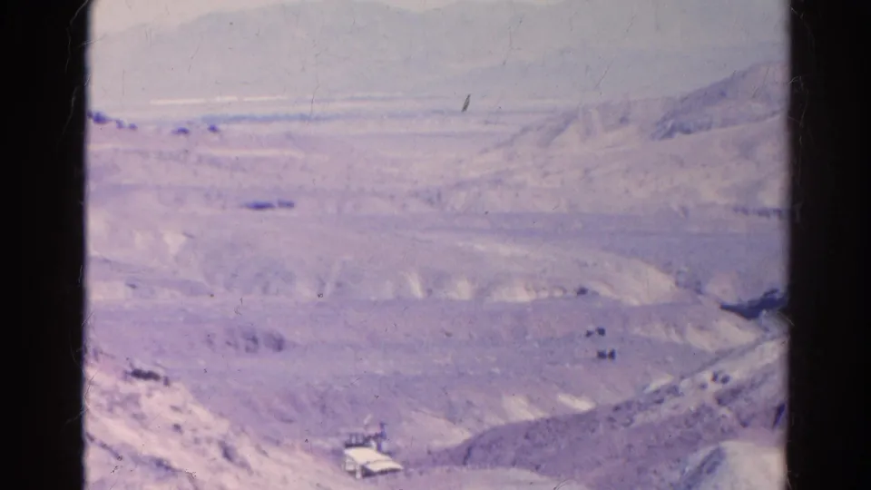 Faded 8mm view of Silver Lake desert terrain, with a small structure or vehicle near a road at the lower edge of the frame.