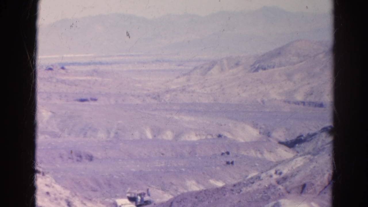 Distant desert hills and mountains with a small rail vehicle near the lower edge.