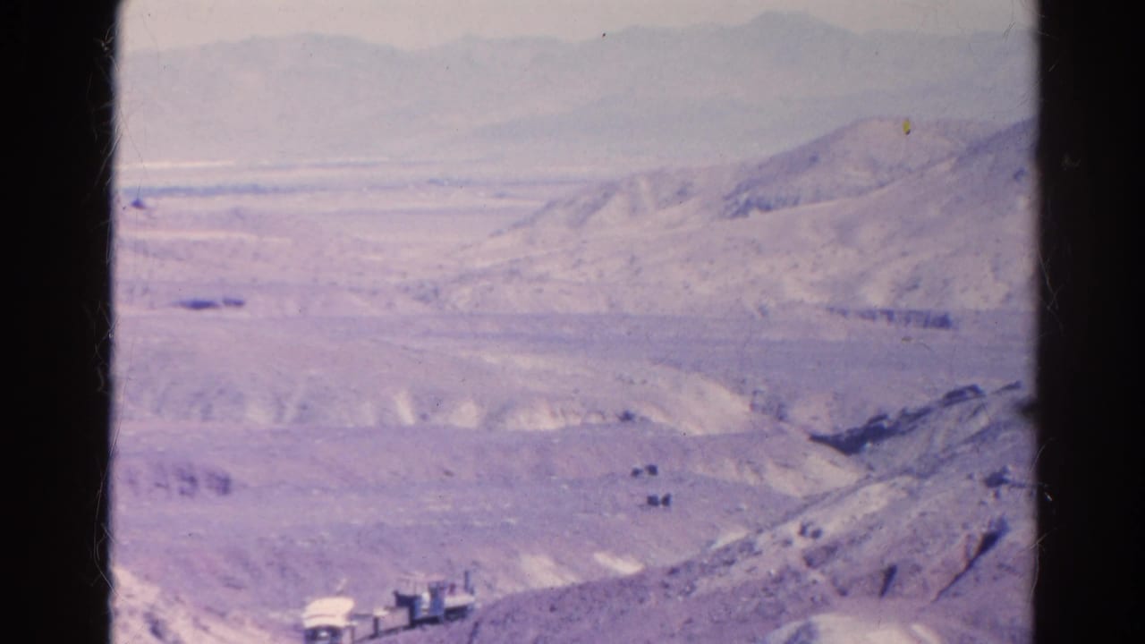 Faded 1966 home-movie frame showing a small rail vehicle below rolling desert hills and a hazy mountain backdrop near Silver Lake, California.