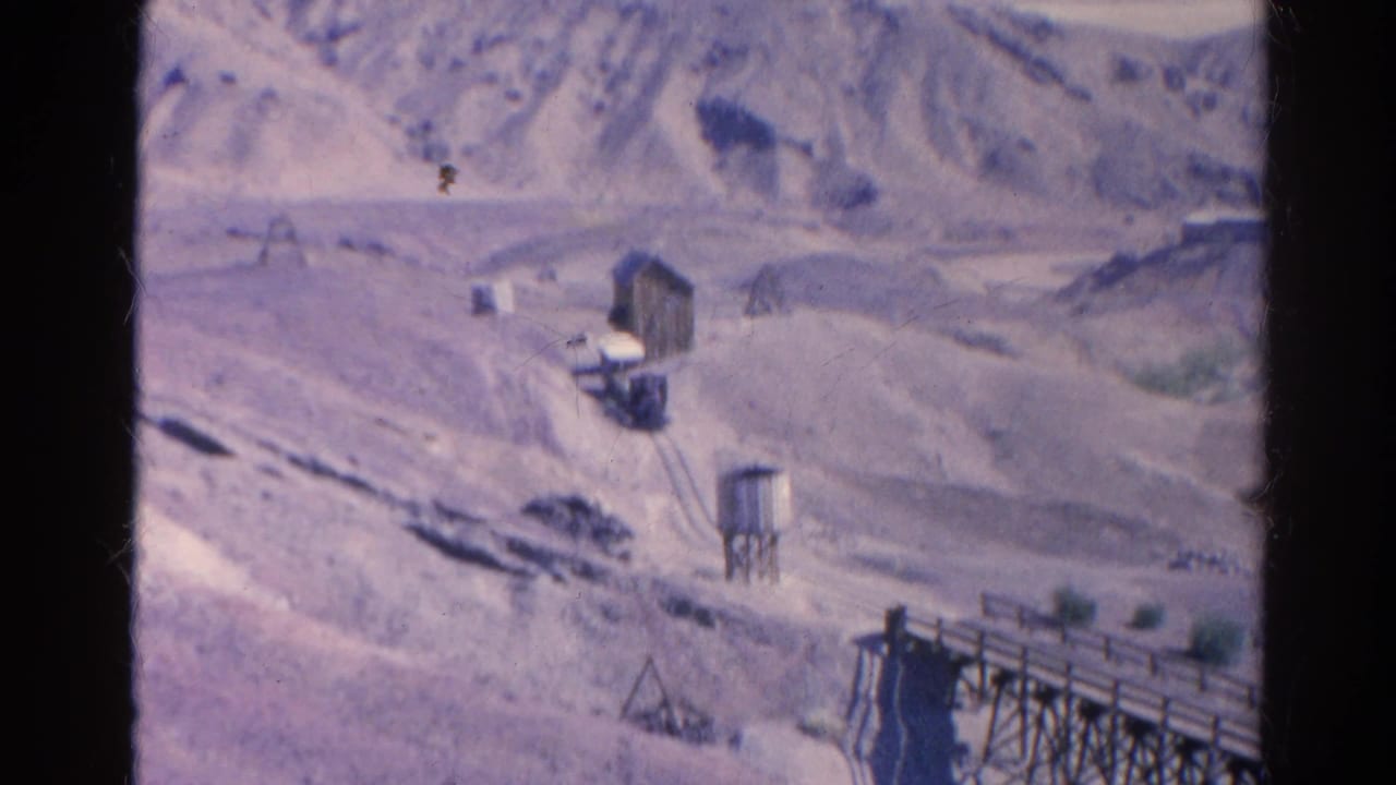 1966 Silver Lake view with arid hills, a water tower, small wooden structures, and a road across the valley.