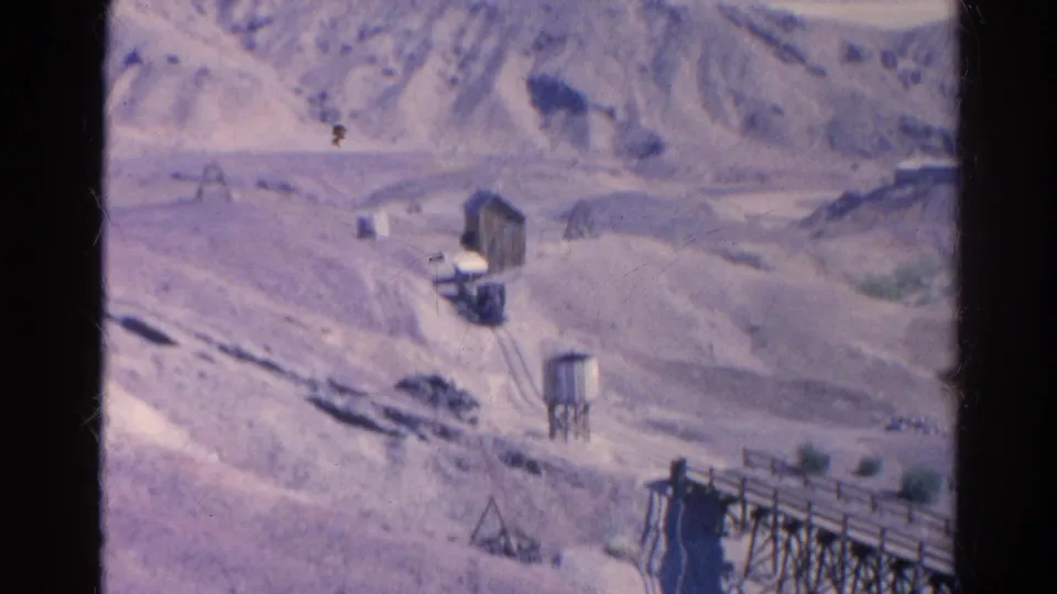 1966 Silver Lake view with arid hills, a water tower, small wooden structures, and a road across the valley.