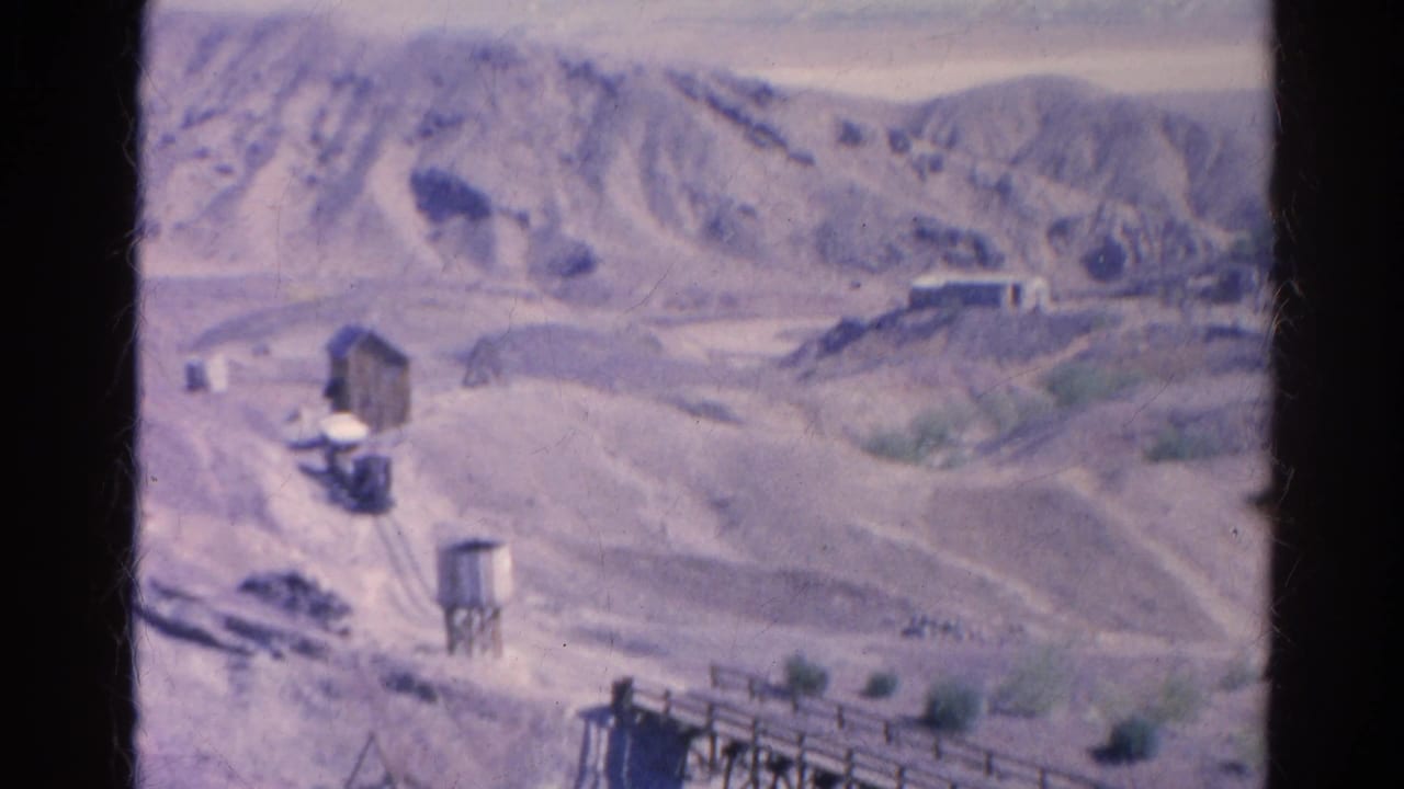 1966 8mm Silver Lake frame showing a small settlement, water tower, pale hills, and rough roads.