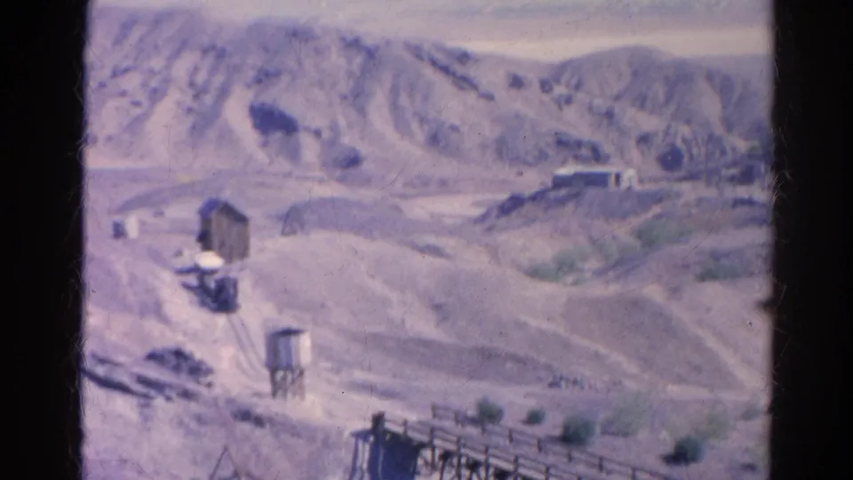 1966 8mm Silver Lake frame showing a small settlement, water tower, pale hills, and rough roads.