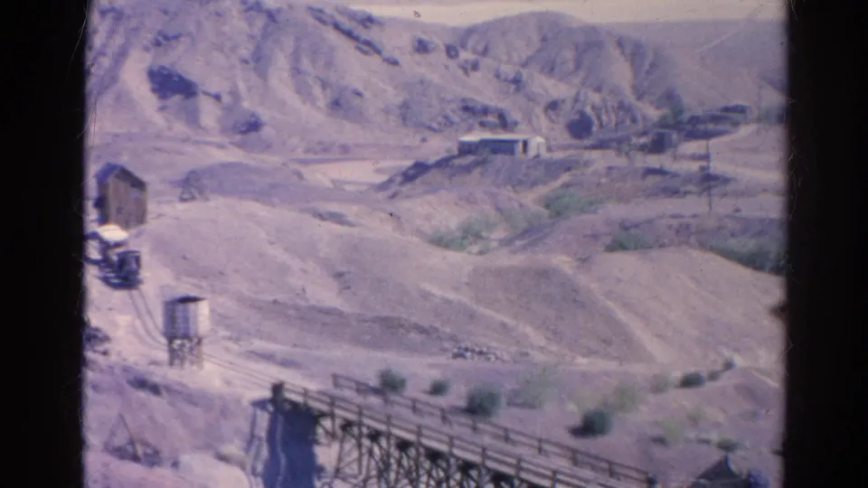 Elevated 1966 view of Silver Lake desert terrain with mining-related structures, rails, a water tank, and a foreground trestle.