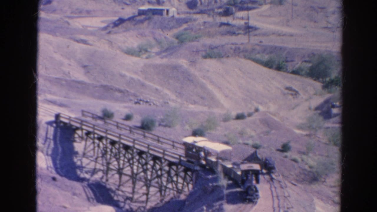 The covered cab of the small train nears the end of the wooden trestle in faded 8mm footage from Silver Lake.