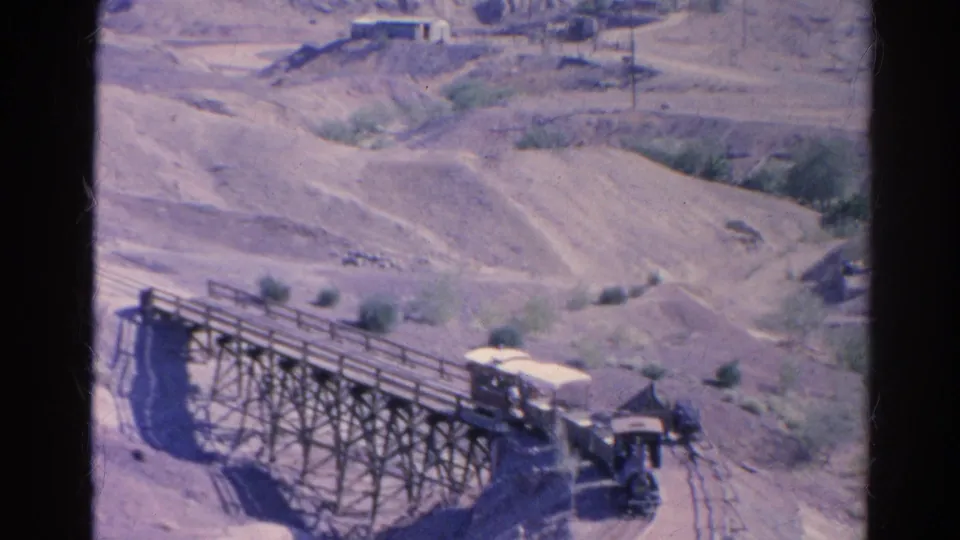 The covered cab of the small train nears the end of the wooden trestle in faded 8mm footage from Silver Lake.