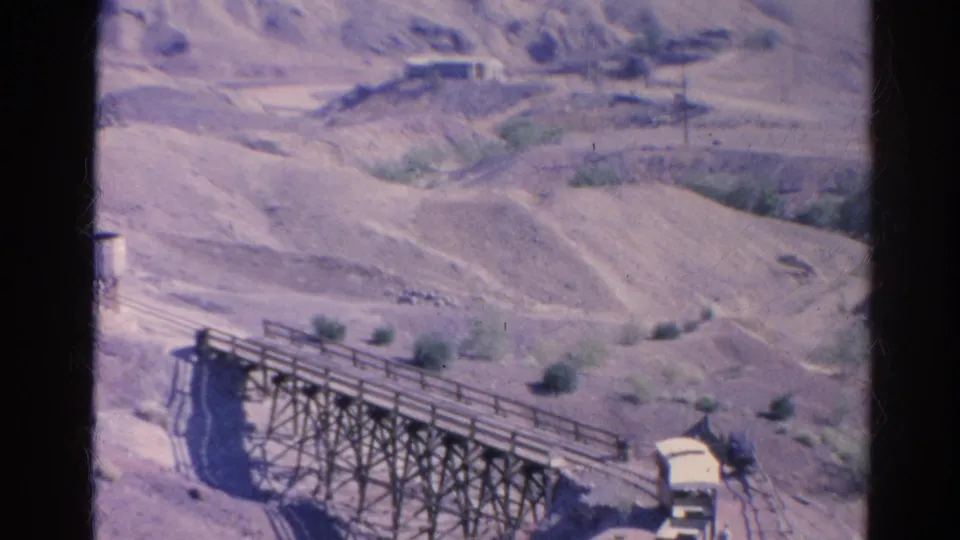 1966 Silver Lake, California 8mm frame showing a wooden trestle or bridge over dry terrain with scrub and hills beyond.