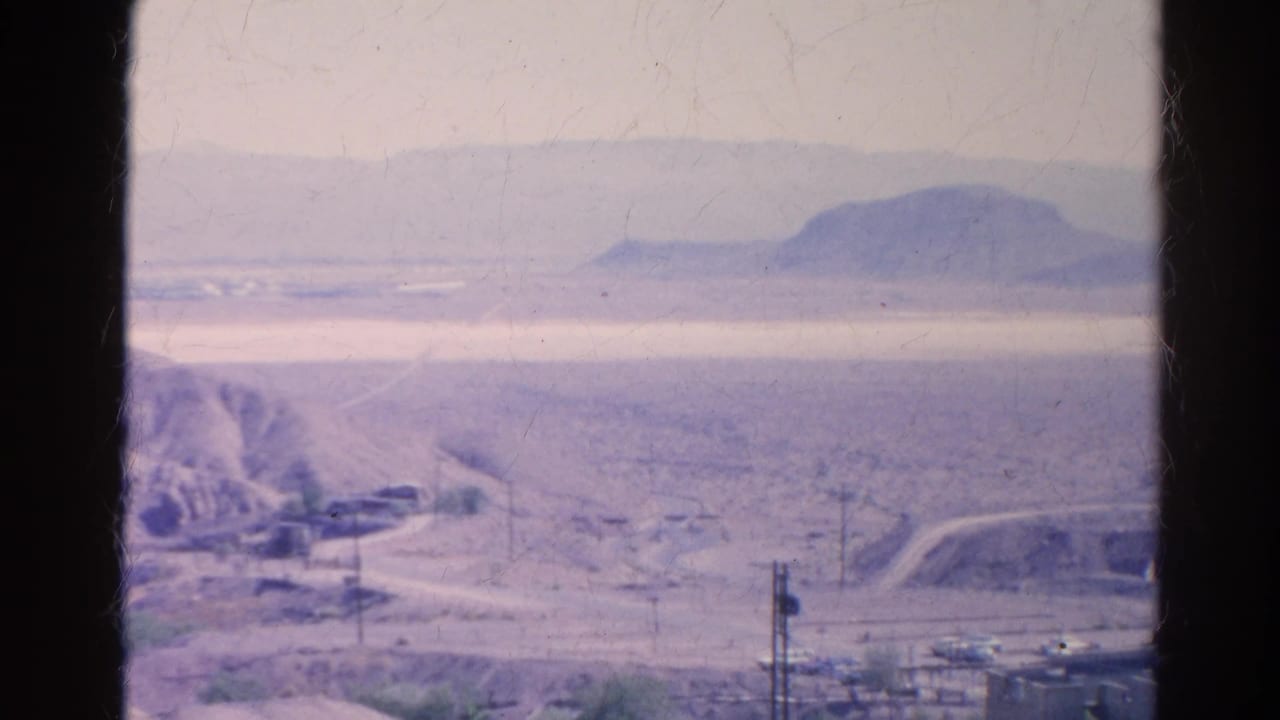 1966 Silver Lake, California 8mm frame showing a pale arid valley, distant hills, road grades, and utility lines.