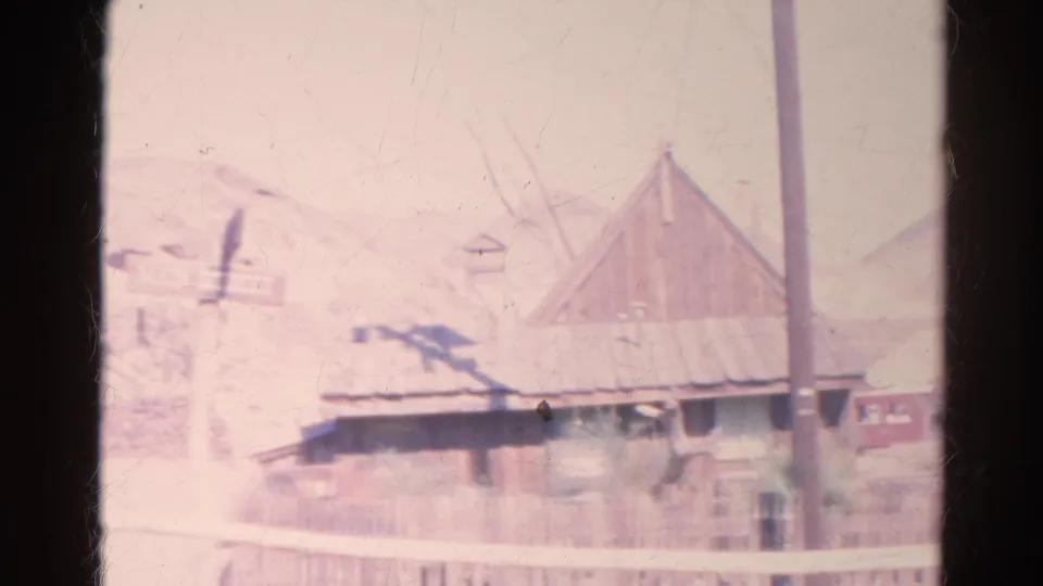 1966 Silver Lake 8mm frame with a weathered building, central utility pole, small sign, fencing, and arid hills.