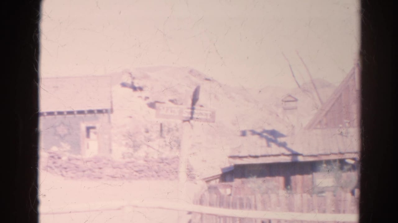1966 8mm frame in Silver Lake, California, with a Main Street sign, rustic buildings, fencing, and pale hillside.