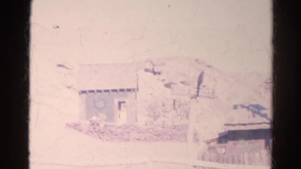 Final 1966 Silver Lake frame showing a pale small building, Main Street sign, partial roofline, fence, and dry hillside.