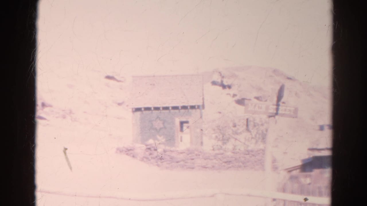 Faded frame with a pale exterior scene and dark 8mm film border.