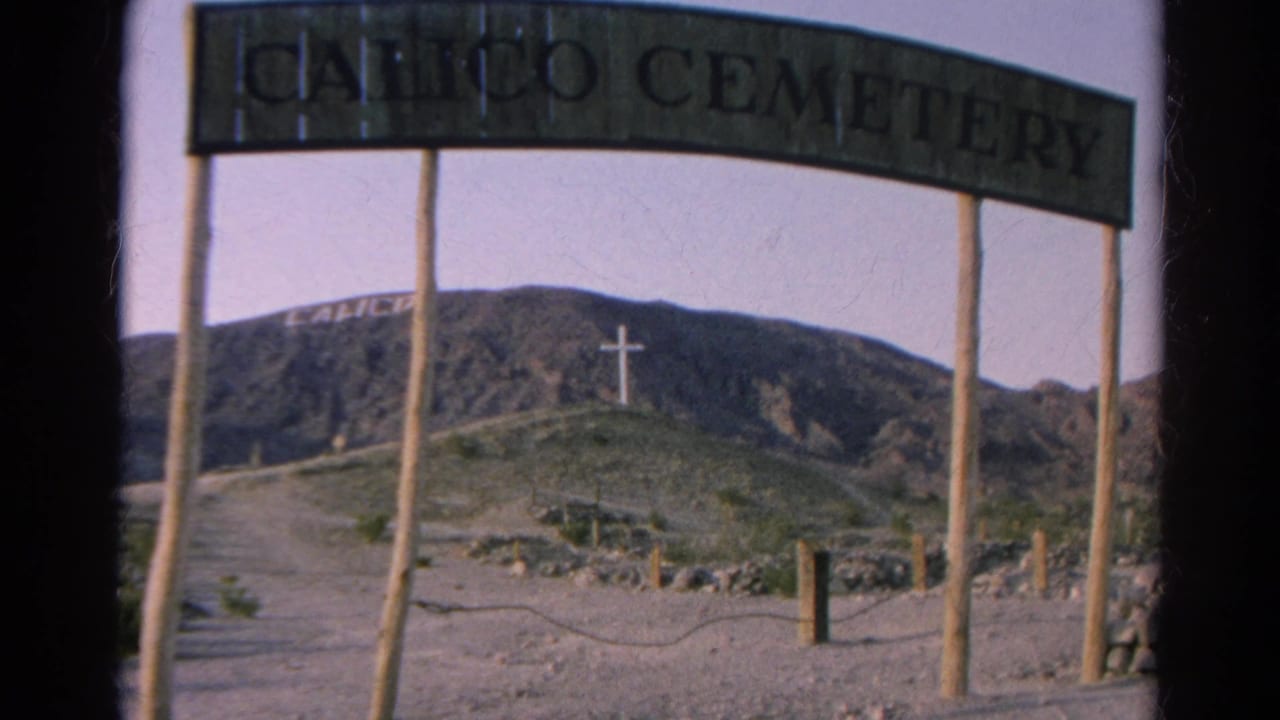 Calico Cemetery entrance appears in 1966 California 8mm footage, with a dirt road, hillside lettering, and a white cross beyond the sign.