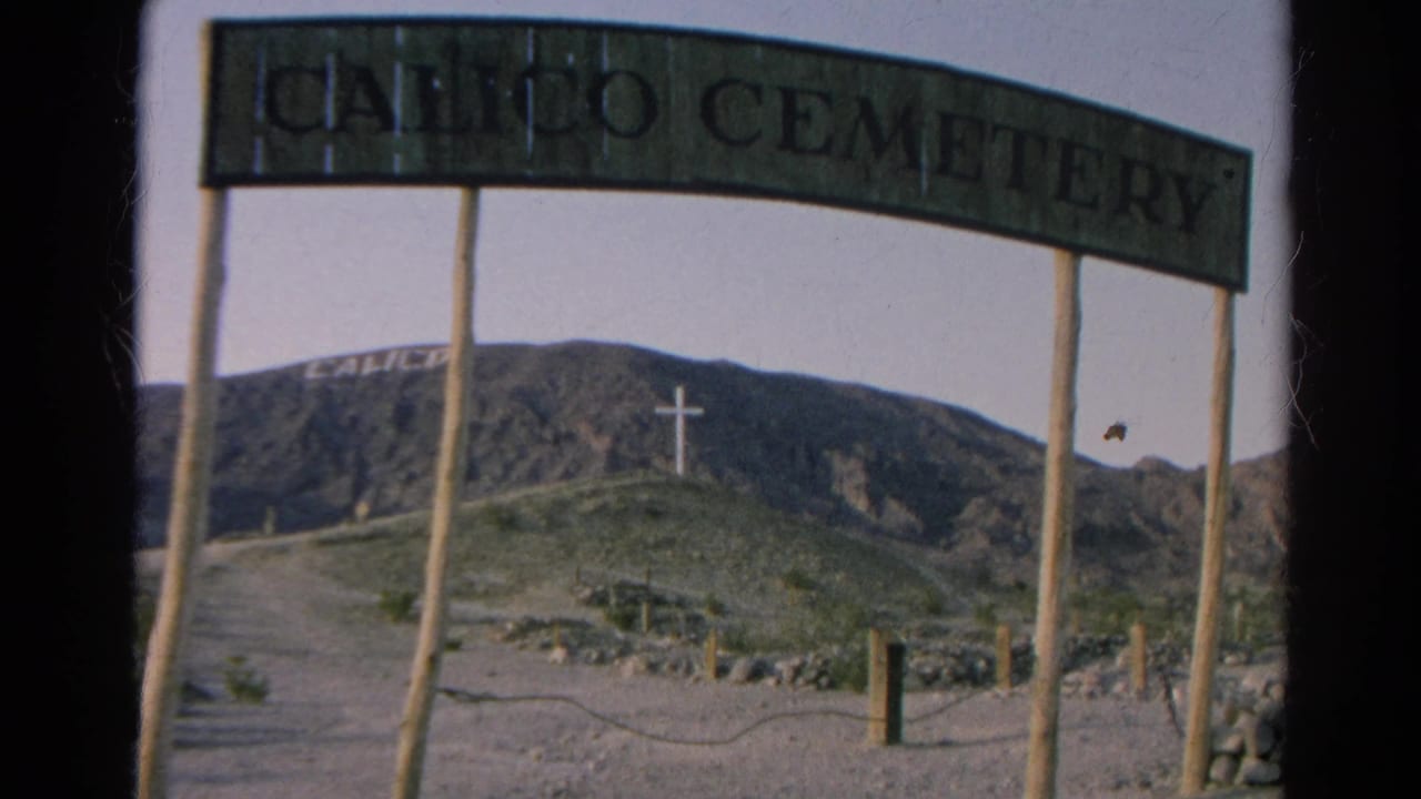 The Calico Cemetery arch remains in view, with a hillside, white cross, posts, and chain barrier visible in 1966 California 8mm home-movie footage.