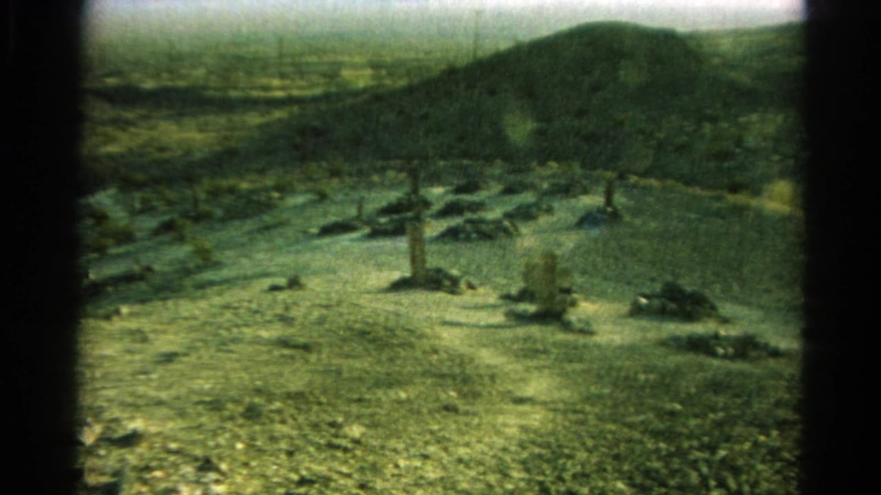 Wide 1966 8mm view of the Silver Lake burial ground set against dry hills, with scattered markers and scrub vegetation across the slope.