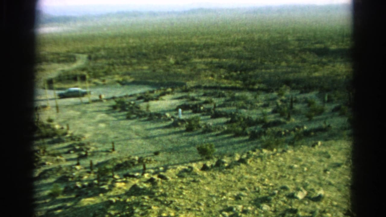 1966 8mm roadside view in Silver Lake, California, showing a parked car near a dirt road, utility poles, scrub, and hazy hills.