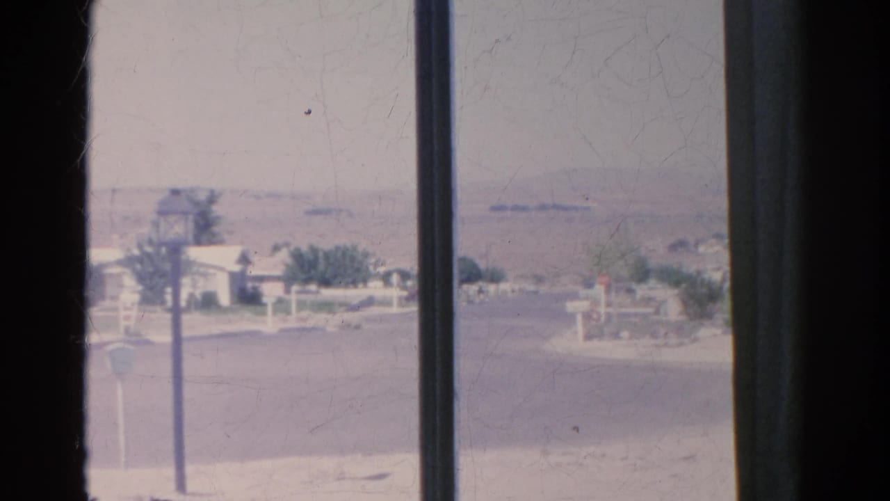 1966 Silver Lake suburban edge with a road, streetlamp, low houses, dry lots, and distant hills framed by vertical window bars.