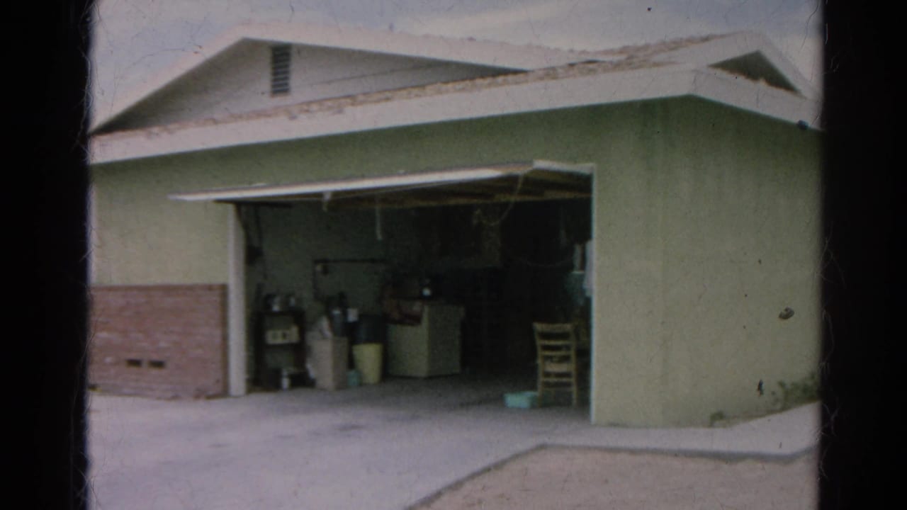 Light green house with an open garage and household items inside.