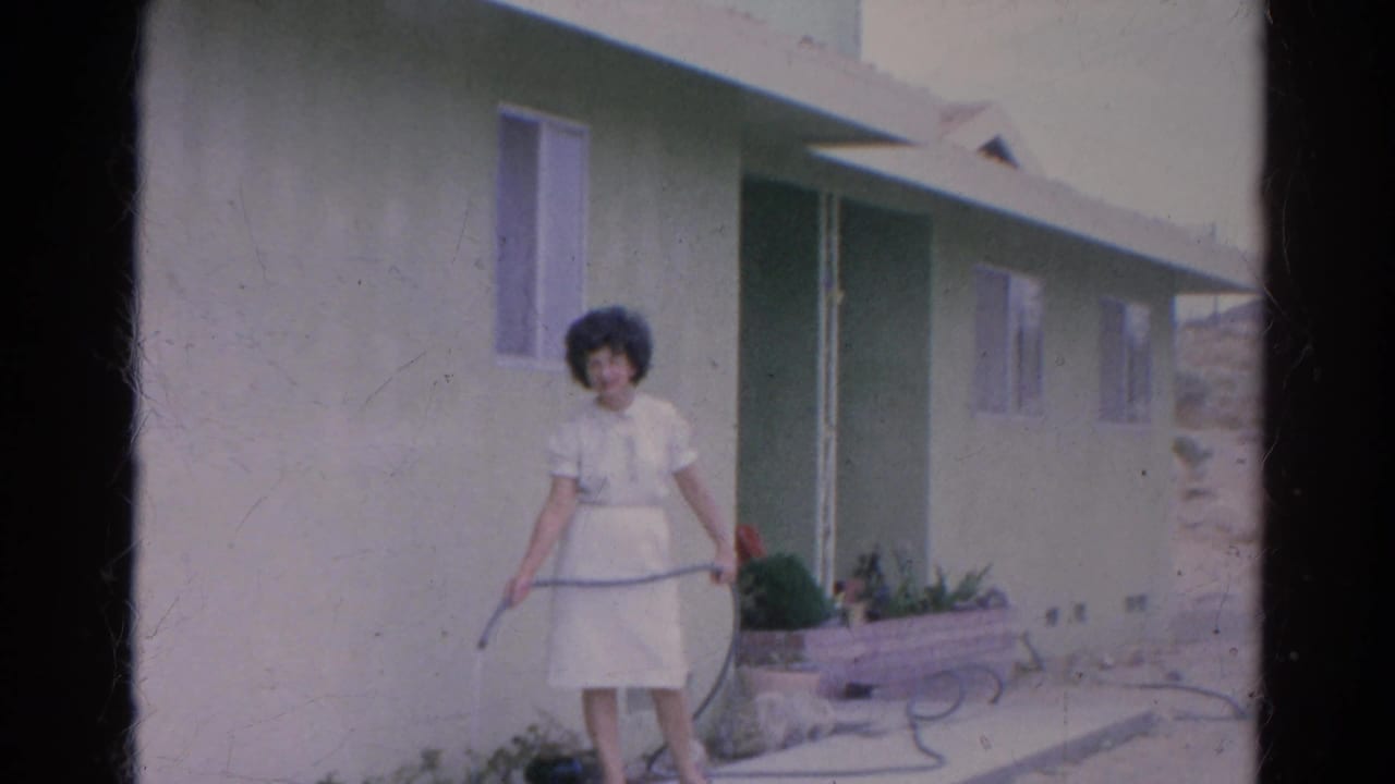Woman in a white dress waters plants outside a Silver Lake stucco home in 1966 home-movie footage.