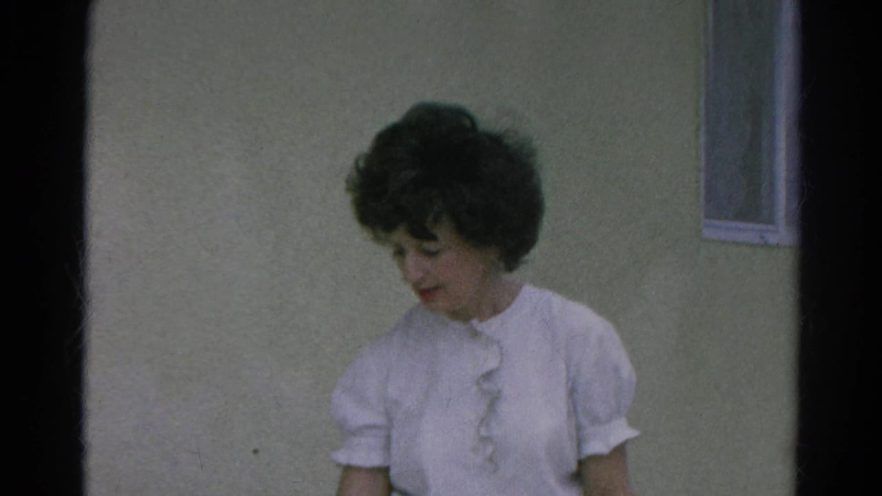 Woman in a white ruffled blouse outside a simple building in 1966 Silver Lake, California home-movie footage.