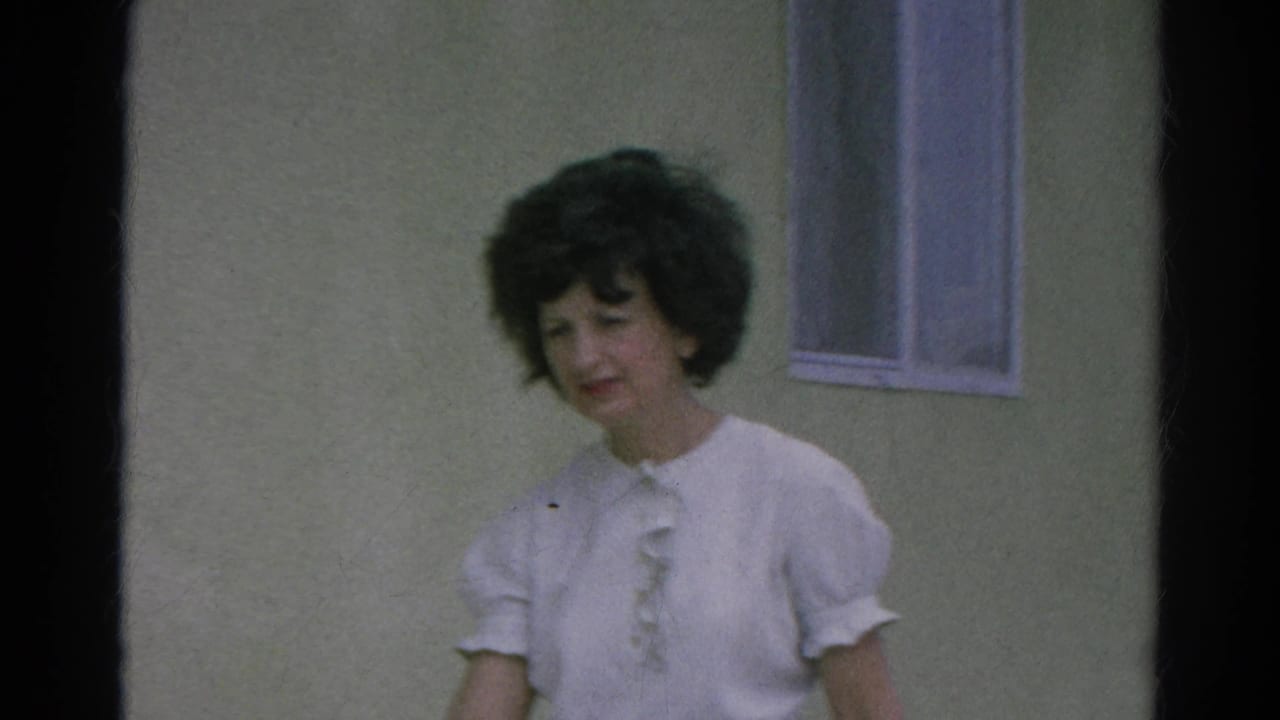 Closer home-movie view of a woman in a white ruffled blouse beside a small window in 1966 Silver Lake, California.