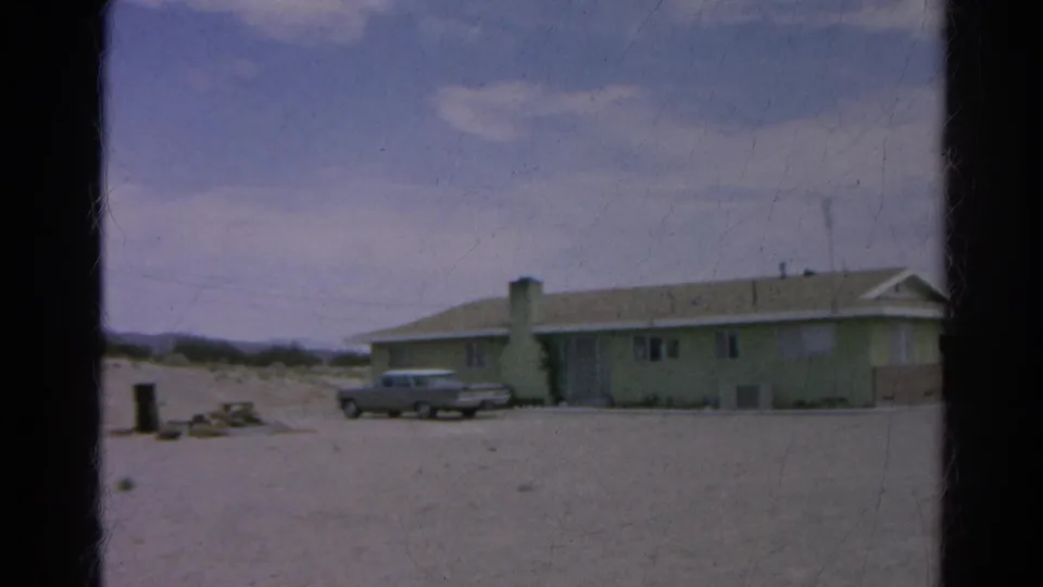 1966 Silver Lake frame showing the sedan parked in front of the pale green house as the camera pan brings more of the building into view.