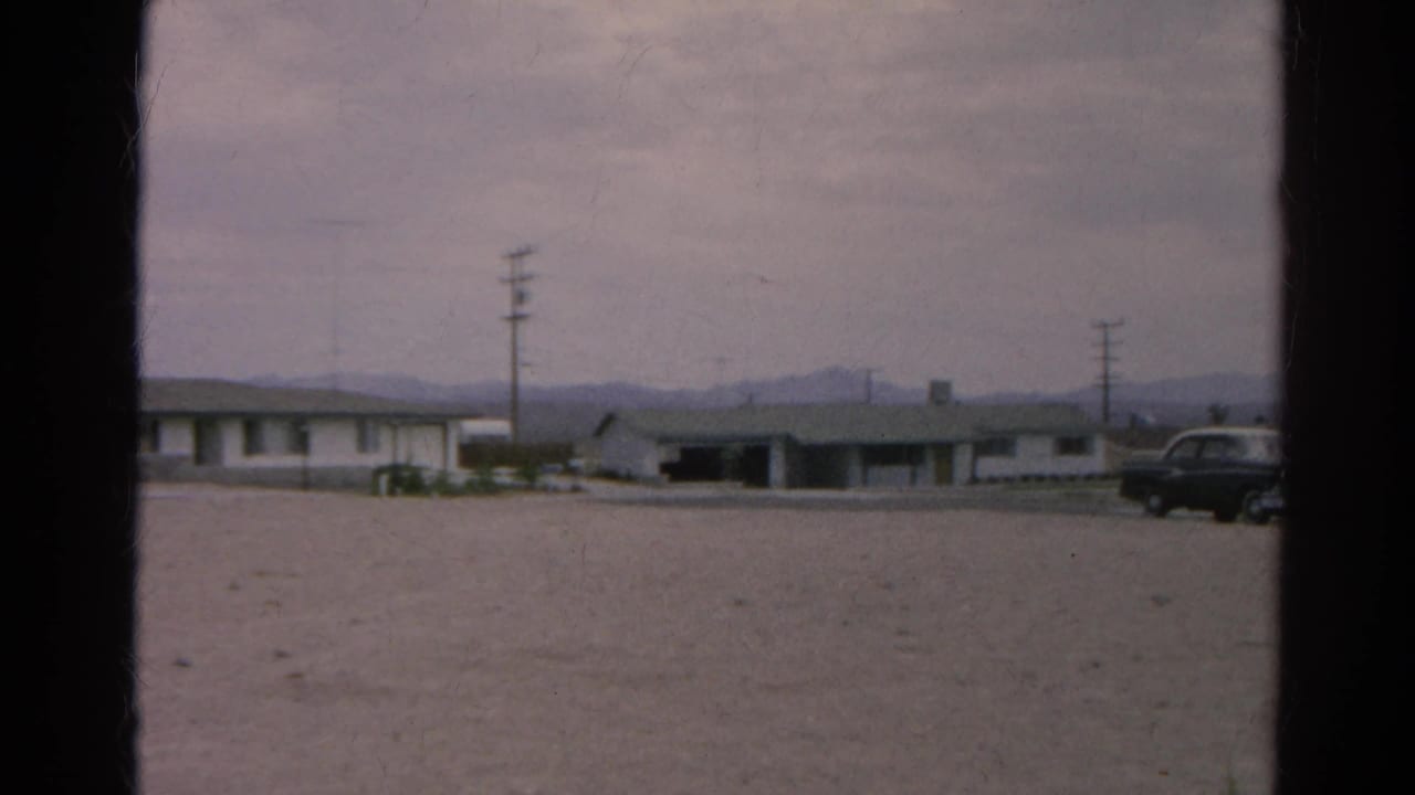 Roadside buildings and utility poles with a dark car partly visible at the right edge.
