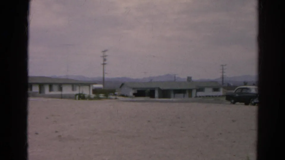 1966 Silver Lake, California roadside view with low buildings, utility poles, distant mountains, and a dark car entering the frame edge.