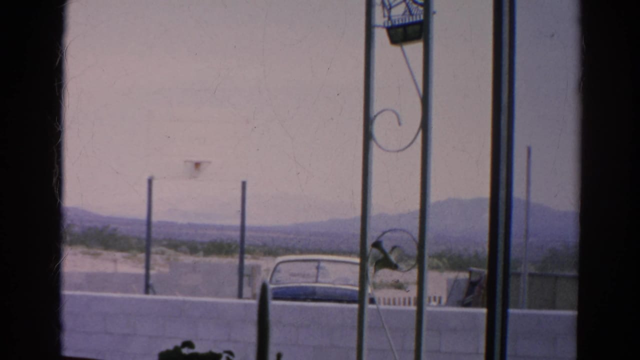 Faded 8mm frame from Silver Lake in 1966 showing a parked car behind a wall and distant hills through a window-like foreground.