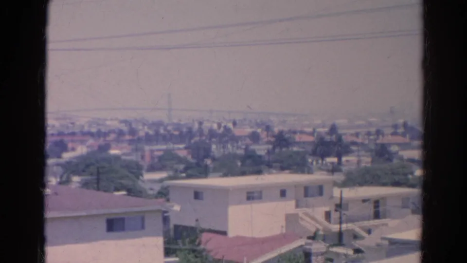 1966 Silver Lake residential view with pale buildings, red roofs, utility wires, trees, and distant Los Angeles haze.