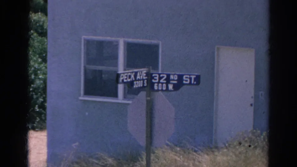1966 Silver Lake street-corner view with Peck Avenue and 32nd Street signs, a pale stucco wall, window, door, and grass foreground.