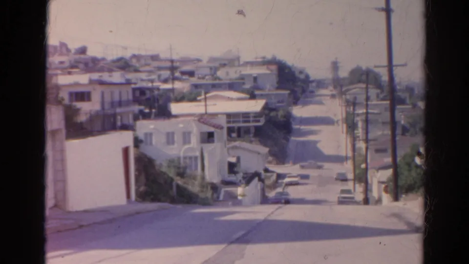 1966 Silver Lake residential view from above a sloping road, with white houses, parked cars, utility poles, and softened 8mm color.