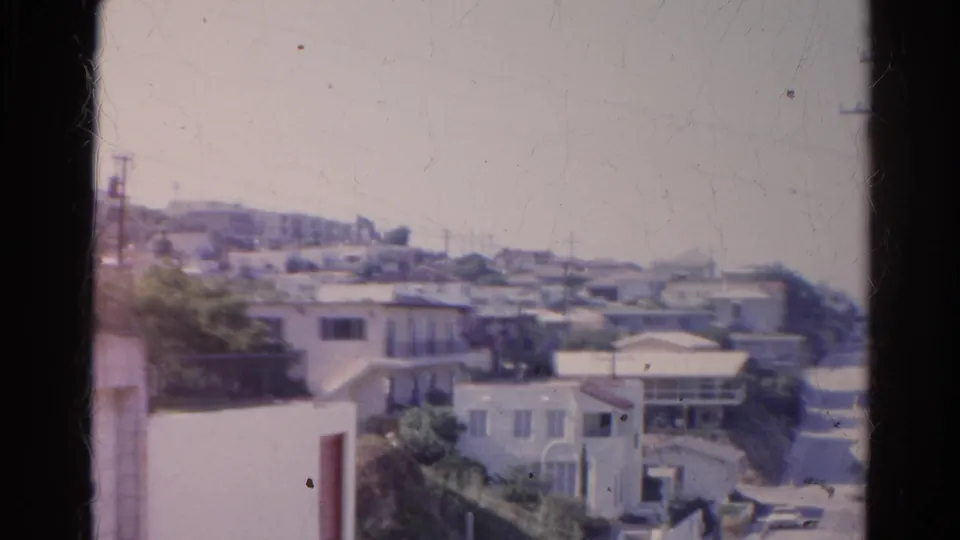 Silver Lake hillside street in 1966 with low residential buildings, visible utility poles, overhead wires, and a few parked cars.