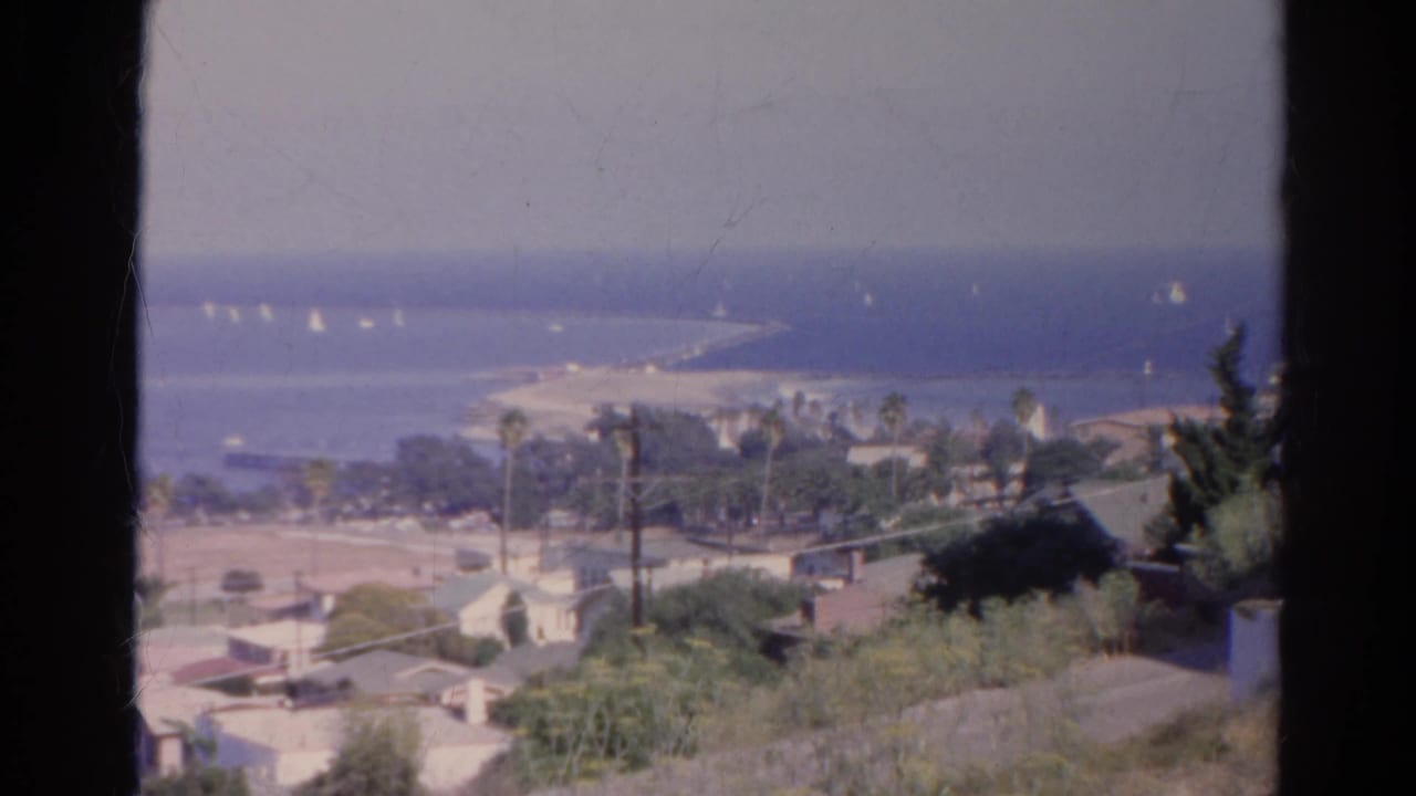 Final 1966 8mm frame holds on the California coastal landscape, showing houses, greenery, palms, beach, ocean, and distant white sails.