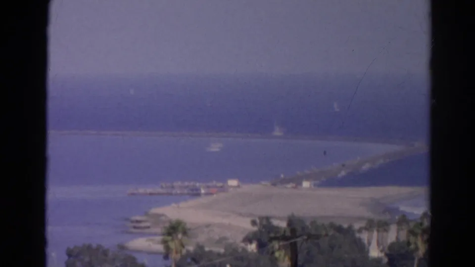 1966 8mm frame from the identified Silver Lake, California clip, with a waterfront pier area, small boats, palms, and hazy blue water.