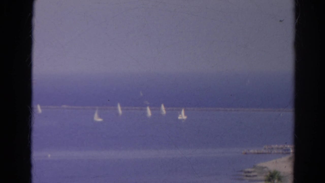 1966 8mm home-movie frame identified as Silver Lake, California, with sailboats spread across blue water beside a long breakwater.