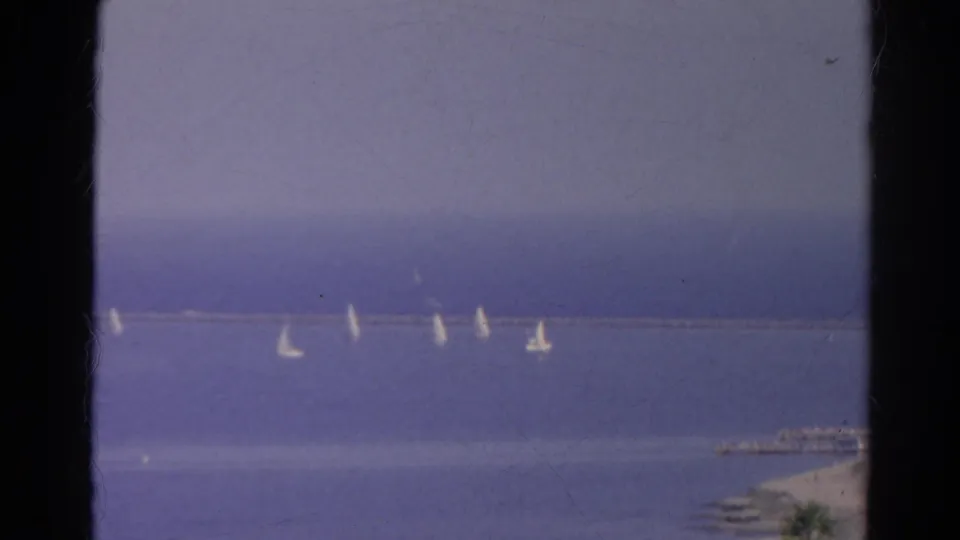 1966 8mm home-movie frame identified as Silver Lake, California, with sailboats spread across blue water beside a long breakwater.